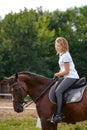 A girl rider trains riding a horse on a spring day