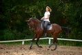 A girl rider trains riding a horse on a spring day