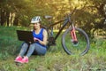 girl rides a biker after a trip to the pine forest and makes a further route on the laptop.