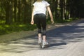 A girl rides roller skates on an asphalt road in the Park in the summer Royalty Free Stock Photo