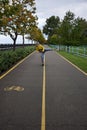 A girl rides a scooter with her foot to the side along the path in perspective and laughs