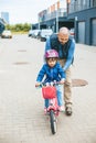 Girl riding a bike with her father\'s hepl. Family outdoors activities together Royalty Free Stock Photo