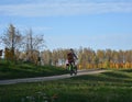 Girl riding on a bike on a rural road autumn landscape blue sky background