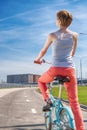 Girl riding on blue folding bike looking at bright cityscape