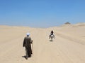 Girl riding donkey and old man following her walking