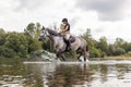 Girl riding gray horse down the calm river water Royalty Free Stock Photo