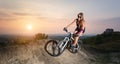 Girl riding on the mountain bicycle against evening sky Royalty Free Stock Photo