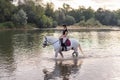 Girl riding a snow white horse down the calm river water Royalty Free Stock Photo