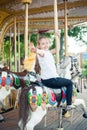 A girl riding a toy horse on a carousel in the park Royalty Free Stock Photo