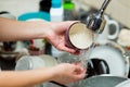 Girl rinses a cup under running water on a background of dirty dishes