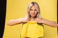 Girl rips rag with her hands yellow on a yellow background beautiful blonde dust tidy cleanup, rubber protective