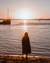 Girl on the riverbank looks at the sunset Royalty Free Stock Photo
