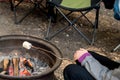 Girl roasting large marshmallow on a stick over the campfire firepit. Camping family fun Royalty Free Stock Photo