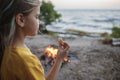 Girl roasting marshmallow to make smores over fire flame during camping, traditional travel food Royalty Free Stock Photo