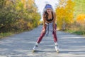 Girl roller skating in the autumn park and listening to the music. Royalty Free Stock Photo