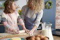 Little girl rolling dough with her mother int the kitchen Royalty Free Stock Photo