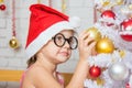 Girl with round glasses hangs balls on a snowy New Years Christmas tree Royalty Free Stock Photo