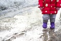 A girl in rubber boots is walking in a puddle. Spring slush. Royalty Free Stock Photo