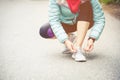 Girl runner tying laces for jogging her shoes on road in a park. Running shoes, Shoelaces. Exercise concept. Sport Royalty Free Stock Photo