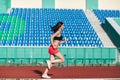 Girl running track on stadium. Real side view of young woman in pink shorts and tank top and pink sneakers. Outdoors, sport Royalty Free Stock Photo