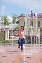 Girl running through the water jets in a fountain. Royalty Free Stock Photo