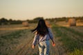 The girl runs across the field, the view from behind, her long black hair flying in the wind, a young woman in jeans Royalty Free Stock Photo