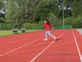 The girl runs across a treadmill at the stadium. Artificial coating for running and sporting events. Sport and athletics. Place of