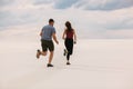 The girl runs away from the guy in the desert, the man wants to catch up with her, the girl is afraid and runs away from him Royalty Free Stock Photo