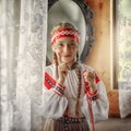 A girl in a Russian dress is holding a Rowan berry beads