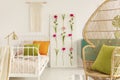 Girl`s bedroom designed in boho style, flower board and macrame on the wall, peacock chair in the corner