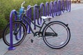 Girl`s bicycle anchored with safety chain to purple bike rack