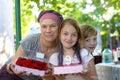 Girl`s birthday. Mom and daughter are holding a cake in their hands. Near the boy