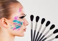 Girl`s face side view with fake eyelashes and colorful face paint makeup brushes Royalty Free Stock Photo