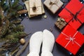 Girl s feet in socks, gift boxes, natural packaging materials, ribbon , branches, pine cone, led garland