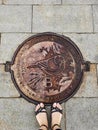 Girl`s feet stand on sewer manhole on Vorobyovy Gory. Bird on hatch is a sparrow - symbol of place Royalty Free Stock Photo