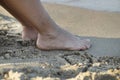 The girl`s feet standing on the sand near the shore