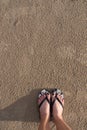 Girl`s feet wearing sandals Which stood on the sand on the beach Royalty Free Stock Photo