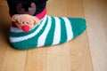 Girl`s foot wearing funny stripey christmas sock with reindeer ornament Royalty Free Stock Photo