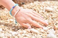 Girl`s hand with a fashion summer bracelet in nautical style on a sea pebbles.