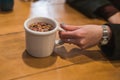 Girl`s hand holding a cup of teacup of rose petals and red berries Royalty Free Stock Photo