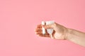 Girl`s hand holding an eco friendly white silicone menstrual cup and tampon isolated on a pink background