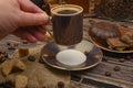 The girl`s hand holds a Cup of coffee over a wooden table with brown sugar, coffee beans and chocolate Royalty Free Stock Photo