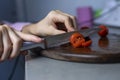 girl's hand holds a knife and cuts a cherry tomato into slices Royalty Free Stock Photo