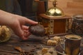 The girl`s hand holds a marshmallow in chocolate, a Cup of coffee, coffee beans, brown sugar, coffee grinder on a wooden Royalty Free Stock Photo