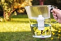 Girl`s hand holds a water filter jug in a summer garden in countryside Royalty Free Stock Photo