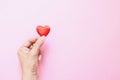 Girl`s hand with mini polka dots red heart on pink background. Valentine`s Day. Heart donation. Love concept Royalty Free Stock Photo