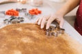 Girl`s hand pressing metal cookies cutter on rollout dough