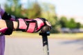 The girl's hand in a protective oversleeve is holding the wheel of a scooter. Cycling and scooter safety concept Royalty Free Stock Photo