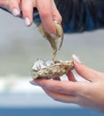 The girl's hand pulls a live fresh oyster out of the shell during a delicious diet lunch outdoors in early spring