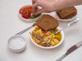 The girl`s hand takes the salad from a small plate. In a deep plate of freshly made soup of turkey, pasta and vegetables